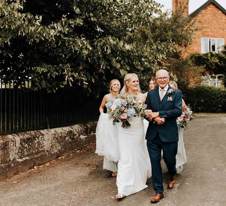 Bride with pastel bouquet makes her way to the church wedding ceremony