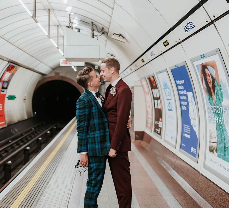 Grooms go in to kiss in tube station on their wedding day  | Kim Williams Weddings