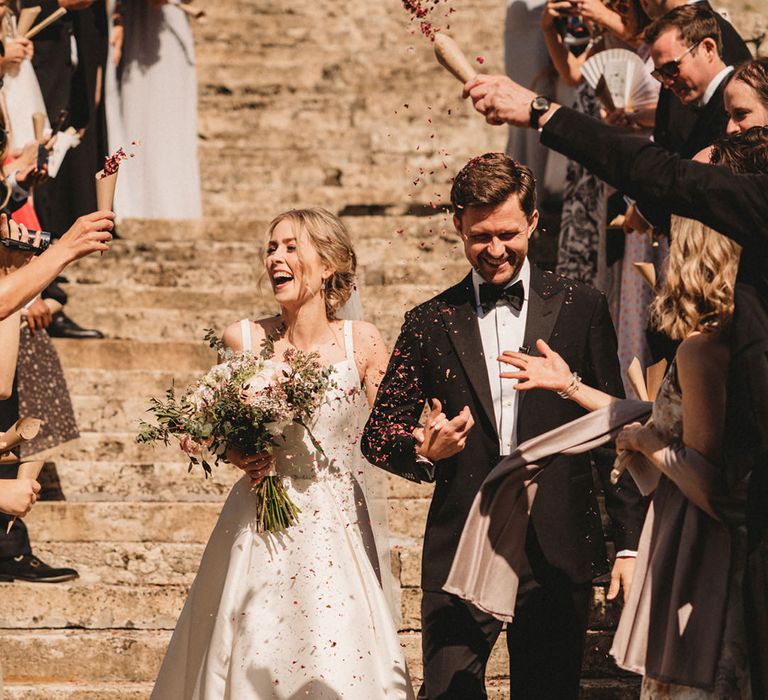 Bride and groom confetti photo on the steps at Chateau Lagorce with bride in a Stella York wedding dress and groom in a black suit