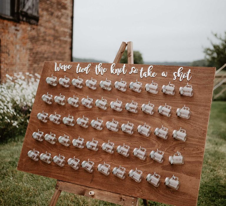 Mason Jars for shots after wedding ceremony against wooden board complete with white wording 