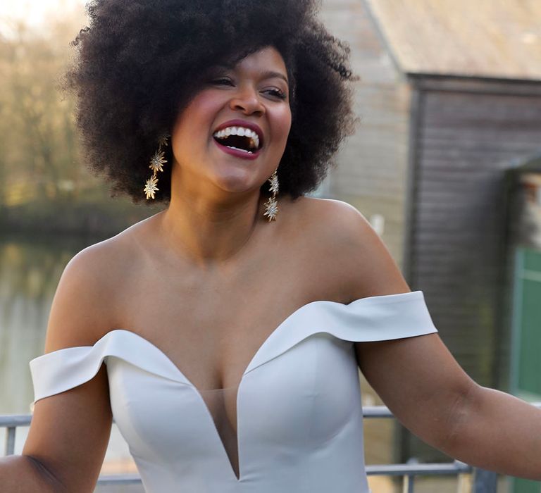 Black bride wears her afro hair natural and off the shoulder wedding gown complete with statement earrings