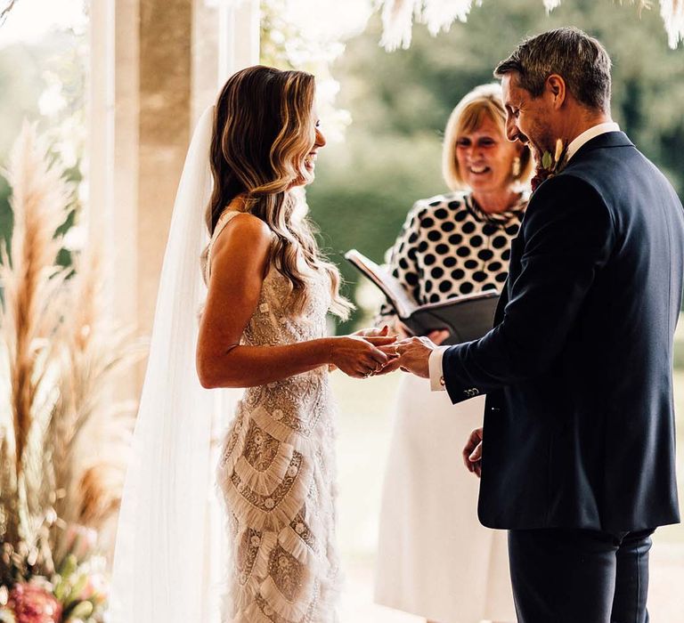 Bride & groom hold one anothers hands during wedding ceremony