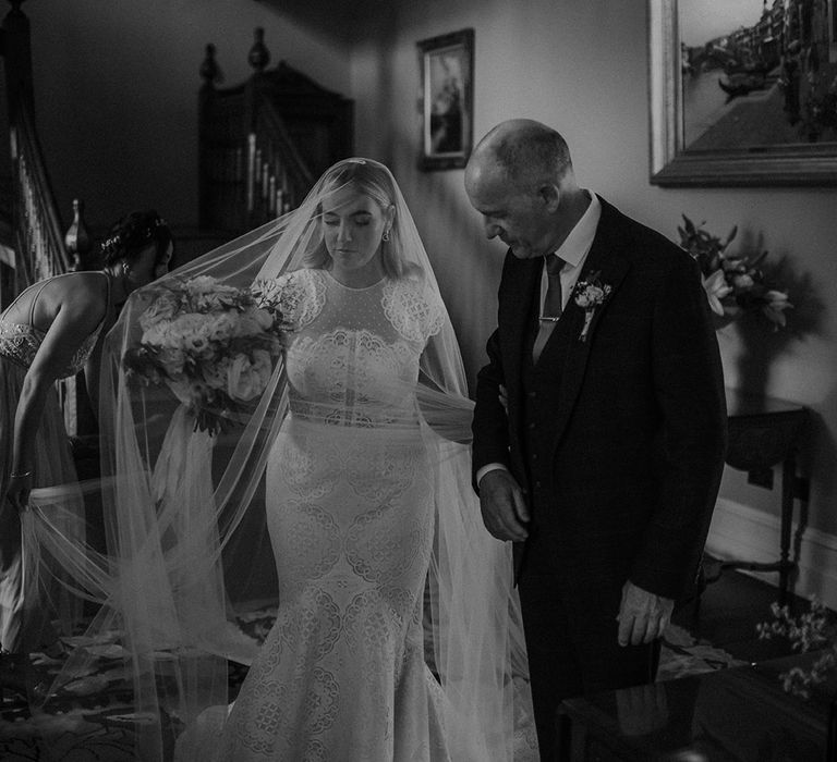 Bride in a Jesus Piero lace cap sleeve wedding dress with her father on the morning of the wedding 