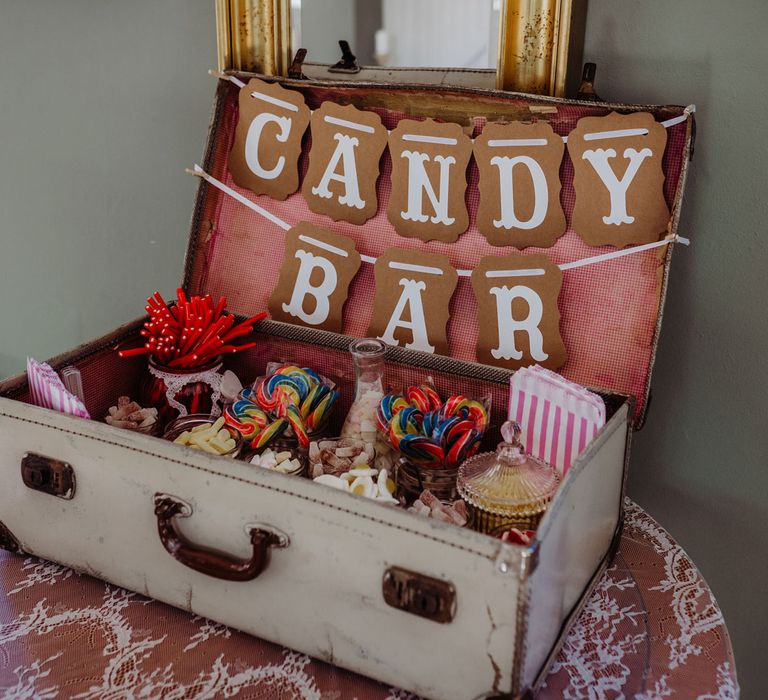 Vintage white suitcase with candy bar sign full of sweets for rustic wedding in the Cotswolds