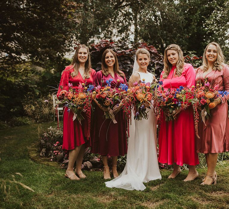 Bridal party in hot pink and magenta pink bridesmaid dresses holding vibrant oversized bouquets 