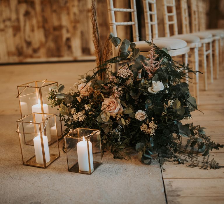 Pink, white and green floral aisle decor with white pillar candles in gold glass candle holders for rustic wedding