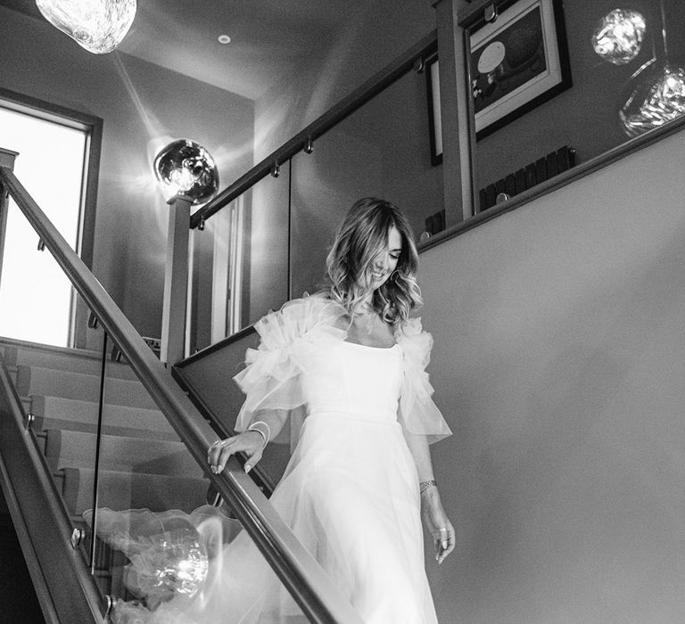 Bride makes her way down the stairs in Halfpenny London wedding dress