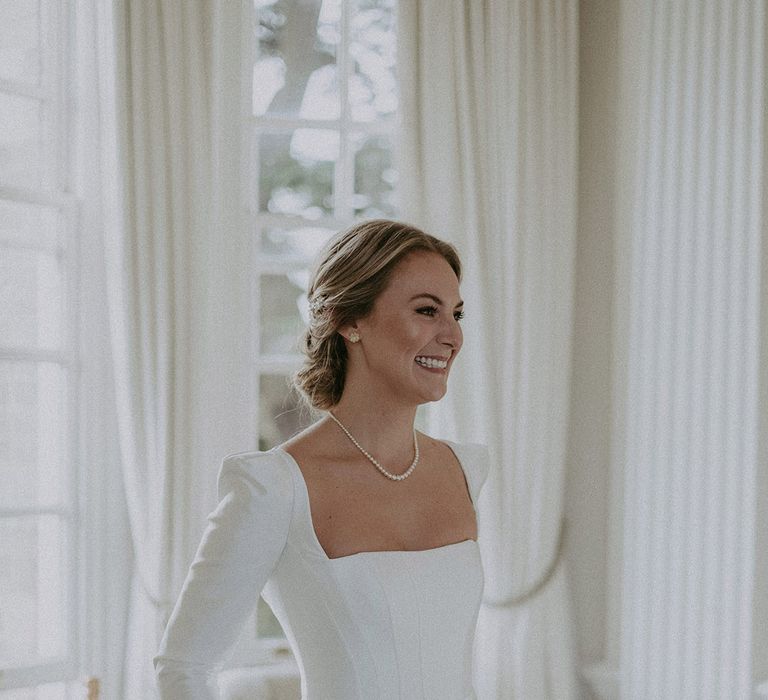 Bride in square neck, full skirt long wedding dress and pearl necklace