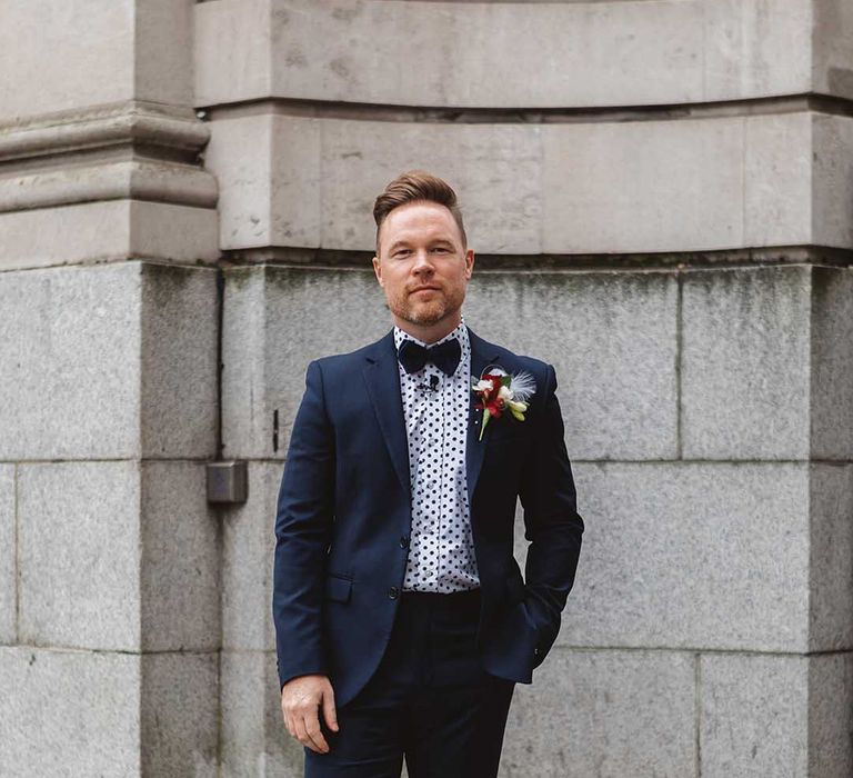 Grooms wears deep blue suit complete with bow tie and polka dot shirt