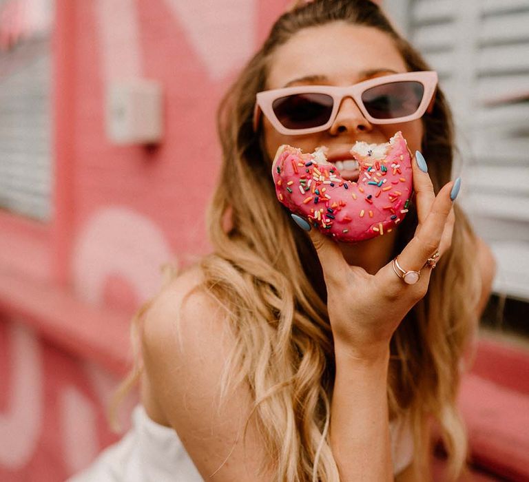 Groom in pink retro sunglasses eating a sprinkle doughnut 