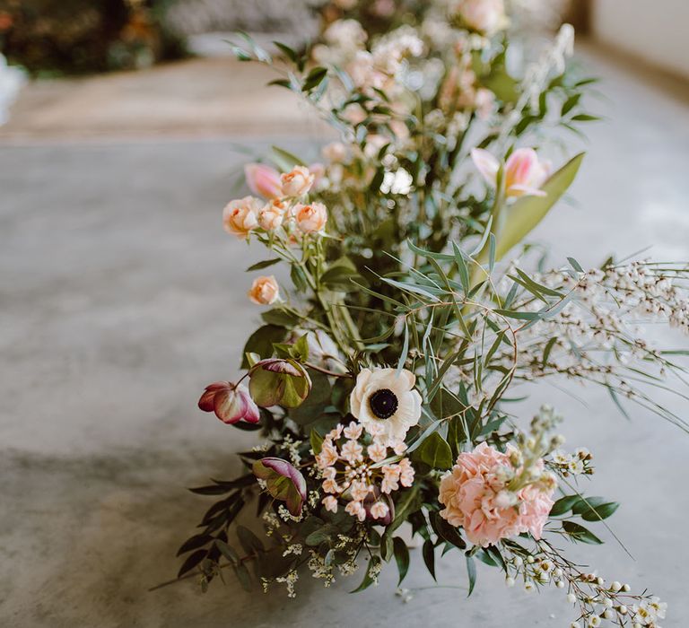 Wedding ceremony aisle flowers with green foliage and blush pink and peach flowers