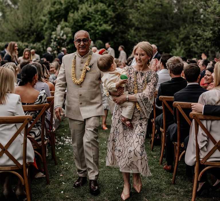 Mother and father of the bride descending up the aisle with their grandson