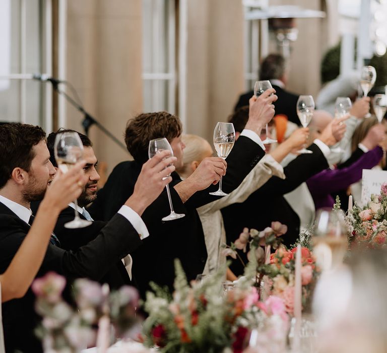 Wedding guests raise their glasses of wine in a toast for the bride and groom 