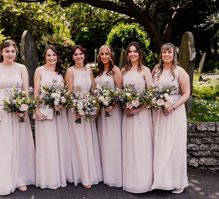 Bridesmaids in blush pink chiffon bridesmaid dresses with pink, purple and white spring bouquets 