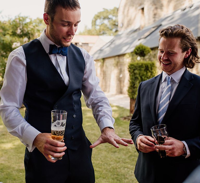 Groom shows off his new wedding band to the groomsmen as he drinks a beer 