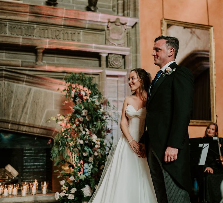 Bride & groom during personal wedding ceremony at Cowdray House in front of pastel florals 