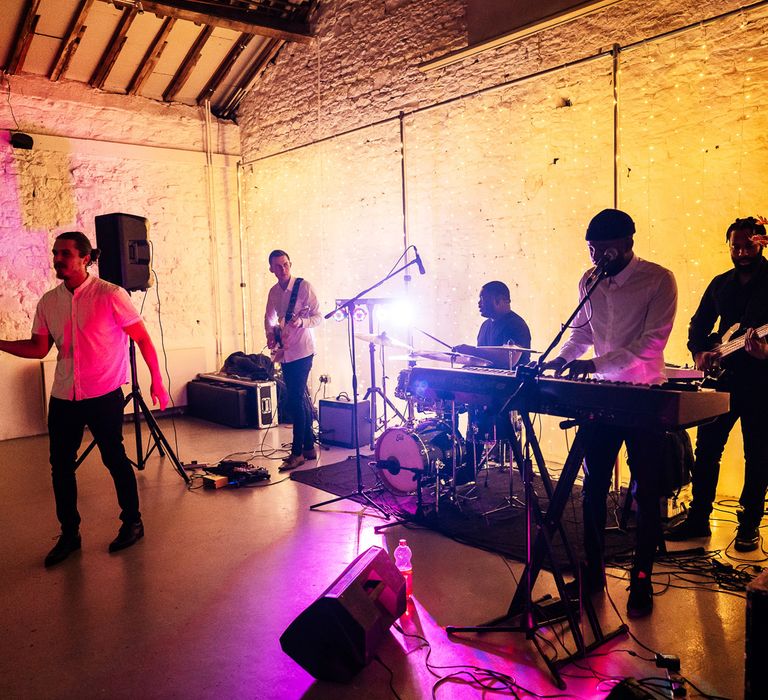 Soul and funk wedding band play for reception surrounded by coloured lights