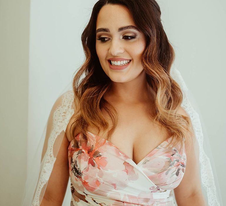 Bride with softly curled hair and smoky eye makeup in a floral wedding dress 