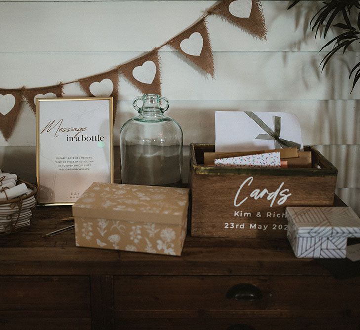 Wooden table with heart bunting behind for cards and 'Message In A Bottle' alternative guest book idea