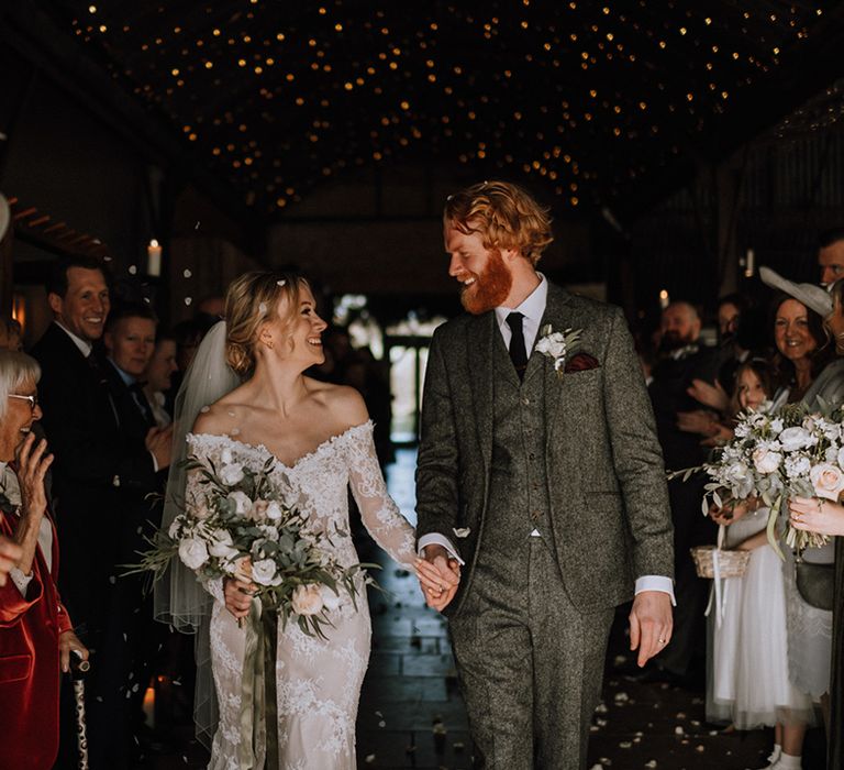 Bride and groom have confetti moment as they walk looking into each other's eyes 