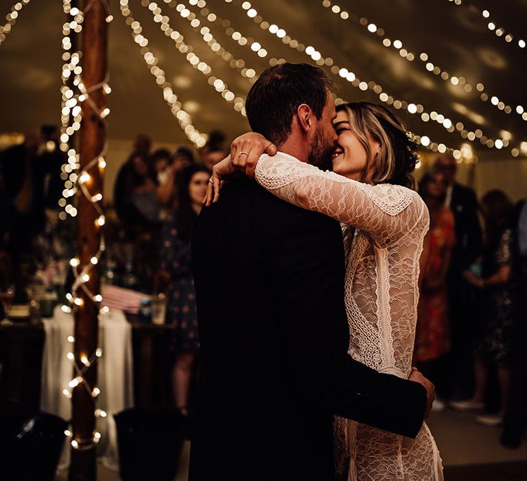 Bride and groom share their first dance together with fairy lights decorating the marquee 