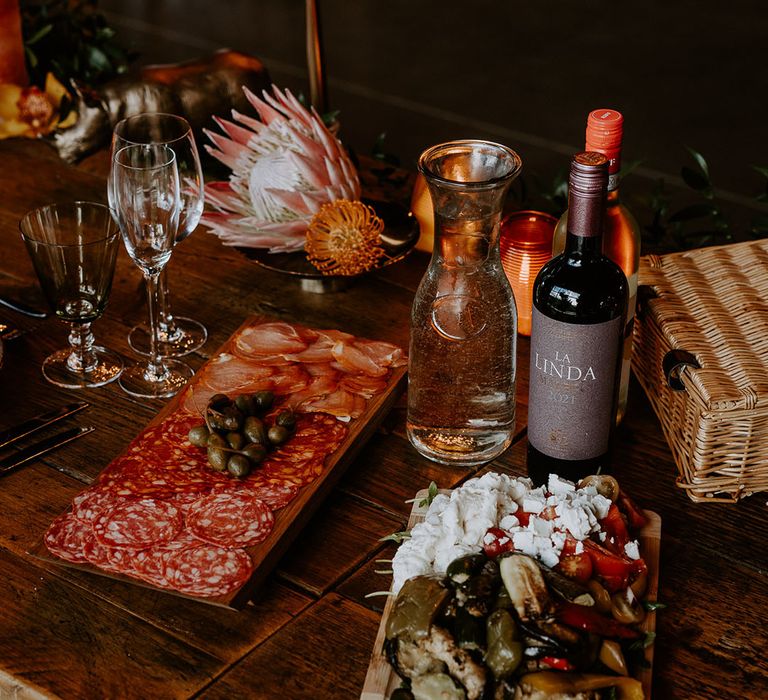 Grazing boards sit on the wedding table with wines with King Proteas and orange wedding flowers 