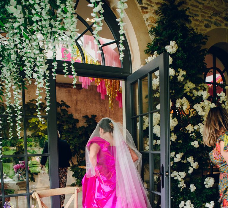 Bride in off the shoulder front ruching pink wedding dress with two layer white and pink ombre veil walking inside Middleton Lodge