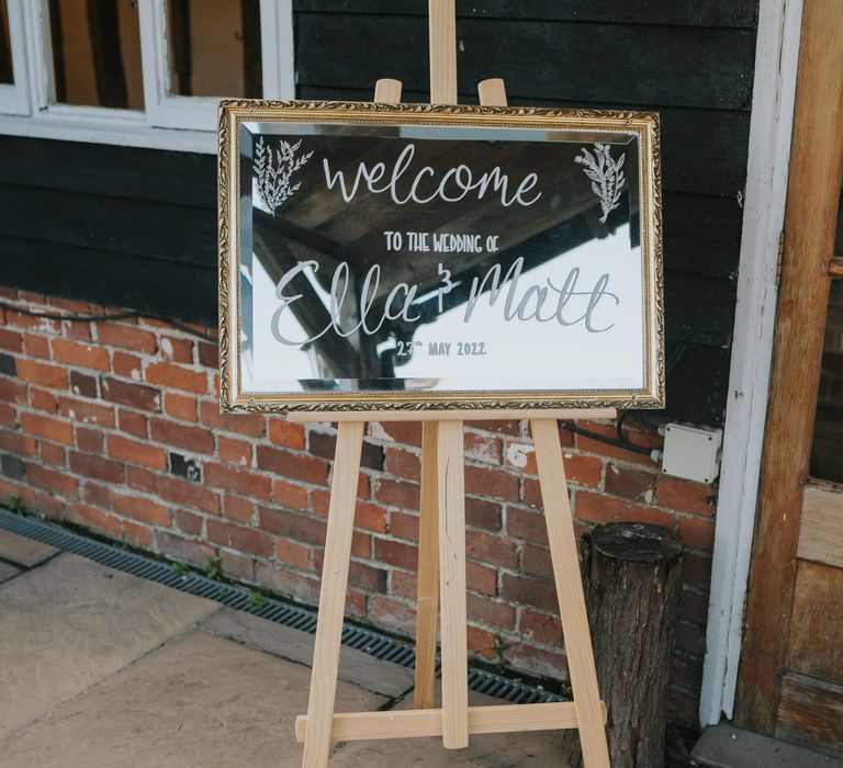 Mirror welcome sign on wooden easel at The Reid Rooms wedding venue