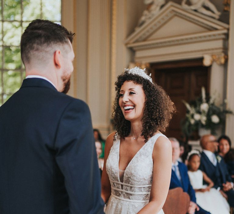 Bride in bridal crown looks lovingly toward her groom during wedding ceremony 