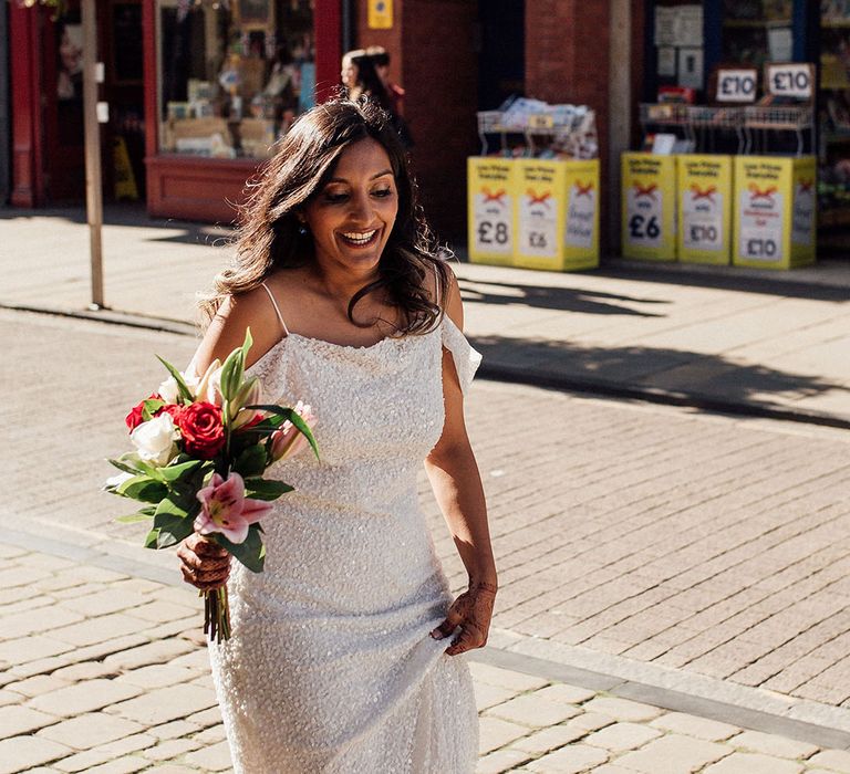 Bride wears off-the-shoulder sequin embellished wedding dress and holds colourful bridal bouquet 