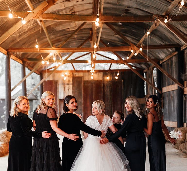 Bridesmaids in mismatched black bridesmaid dresses posing with the bride for bridal party shots at Silchester Farm