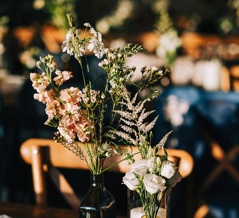 Dark vases with white and pink flowers with white pillar candle decorating the wedding tables 