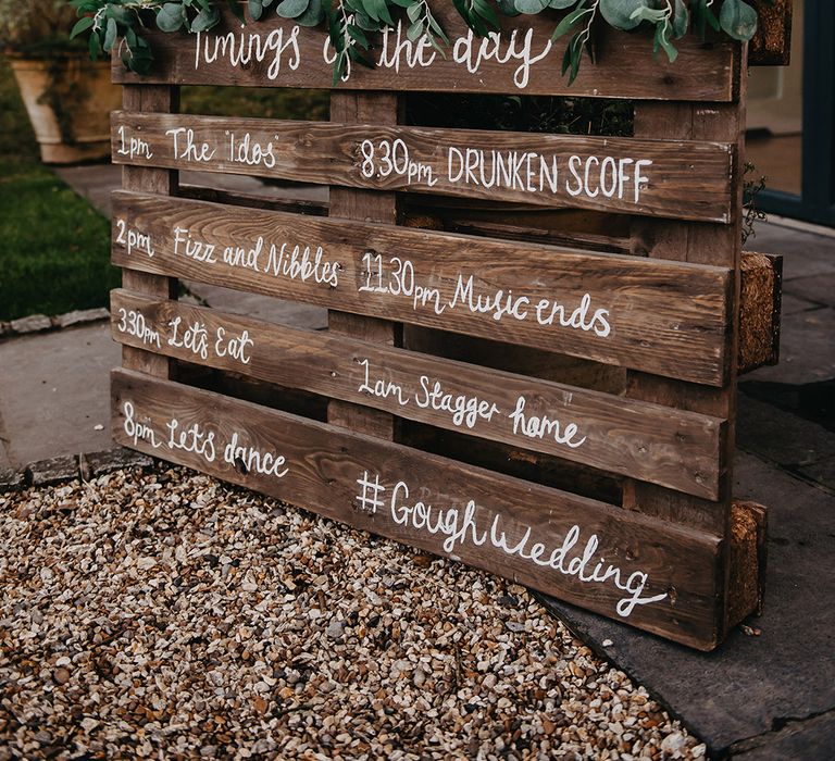 DIY rustic order of the day wedding signage decorated with foliage 