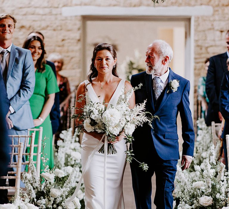 Father of the bride in navy suit with patterned tie walking the bride down the aisle for classic style wedding 