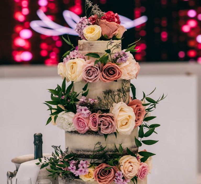 Four tiered semi-naked wedding cake with garden rose and foliage wedding cake toppers