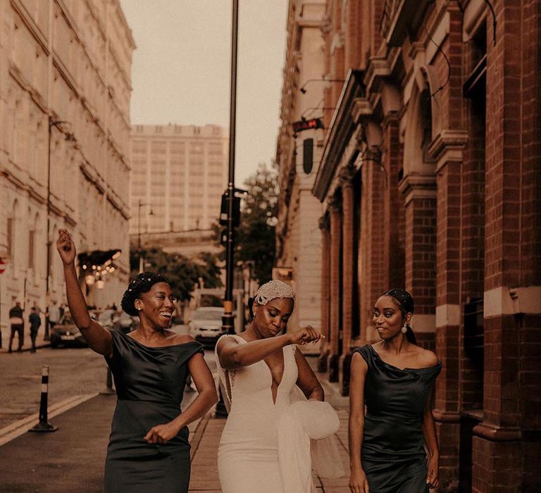 Bride wearing pearl Juliet cap walking the streets with two bridesmaids in autumnal green gowns