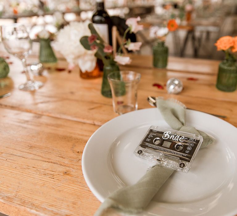 Cassette retro wedding place names on green napkins decorating white plates 