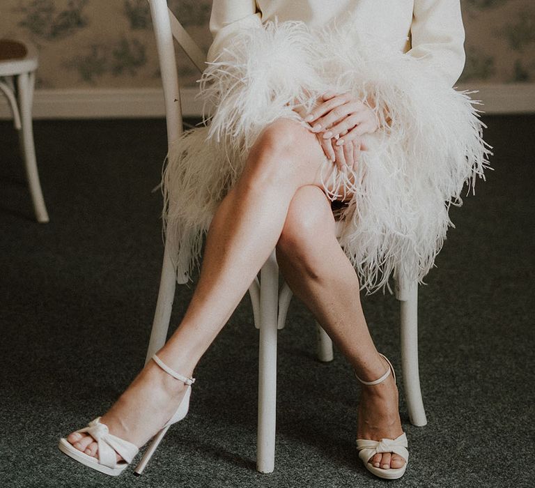 Bride in high neck long sleeve feather wedding dress in white Jimmy Choo wedding shoes 