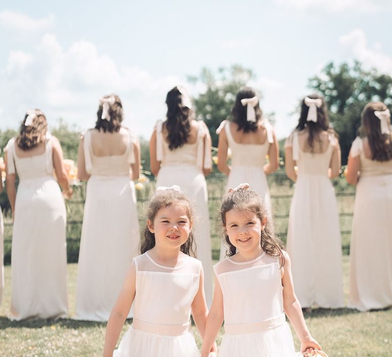 Flower girls in white dress and trainers carrying baskets