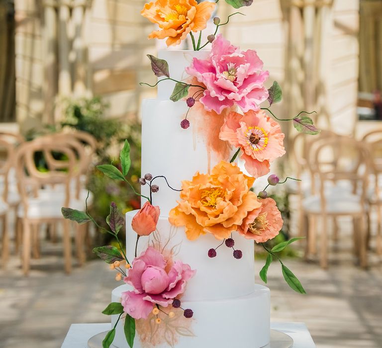 White iced tiered wedding cake with pink and orange colourful wedding flowers 