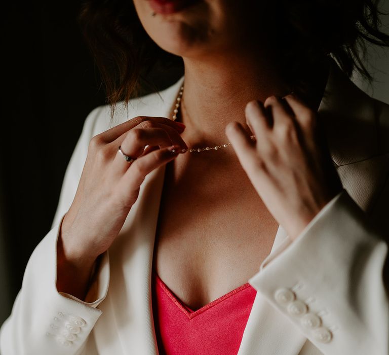 Bride wearing white bridal suit jacket with pink heart shaped top 