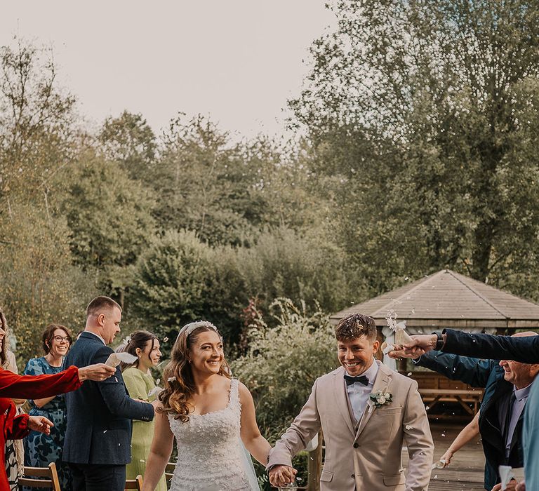 Bride in custom gown with the groom in a beige suit with a black bow tie 