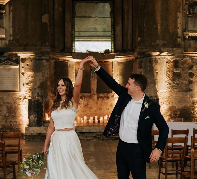 Bride wears lace bridal separates crop top with capped sleeves and high-low bridal skirt by Joasis Photography