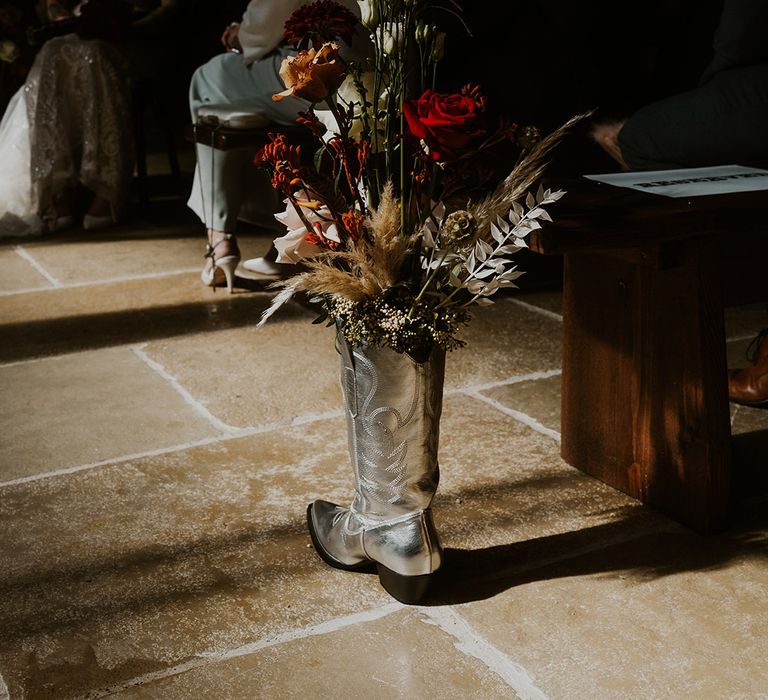 Silver metallic cowboy boot aisle decoration filled with flowers for rustic Western theme wedding 