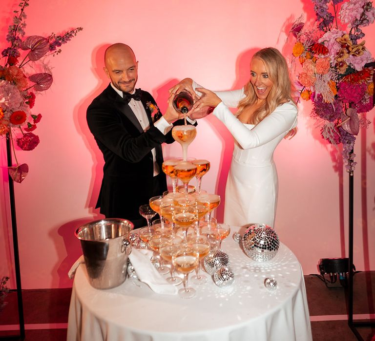 Bride and groom pouring champagne over champagne tower decoration