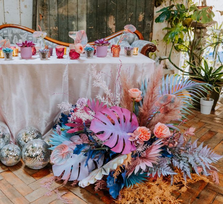 Sweetheart table at festival wedding with holographic pastel wedding decor and flowers 