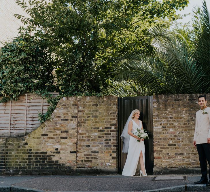 Bride in wedding dress with front split and groom in bespoke suit 