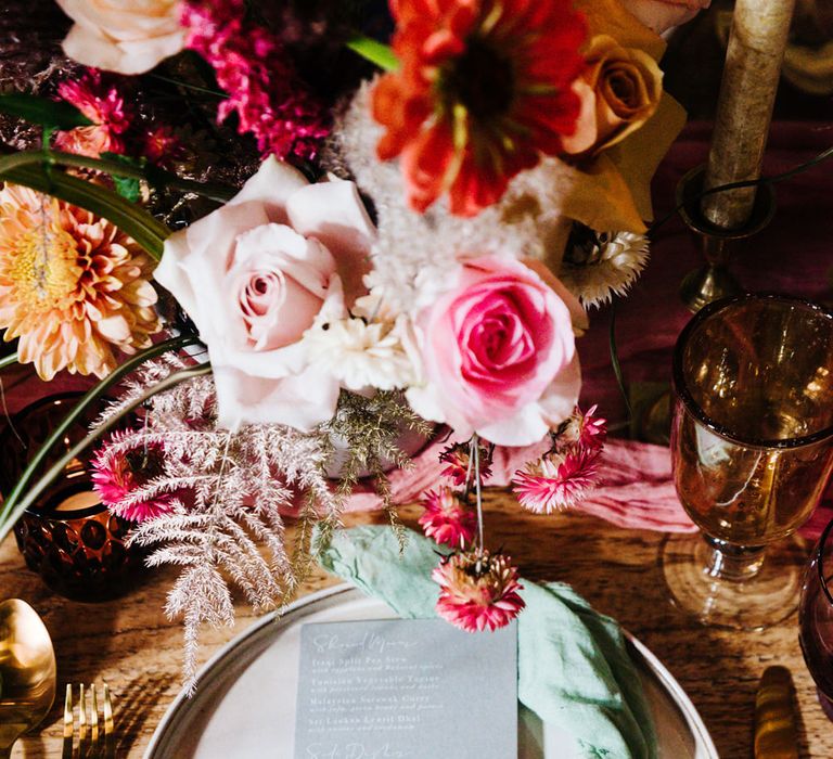 Place setting with coloured linen and menu card surrounded by bright flowers 