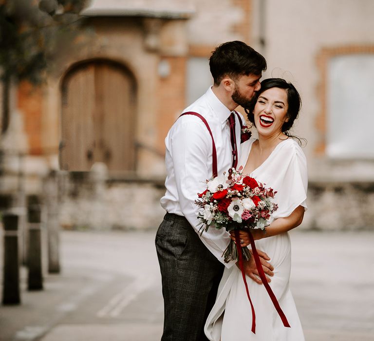 Laughing Bride and Groom in Oxford with red carnation bouquet