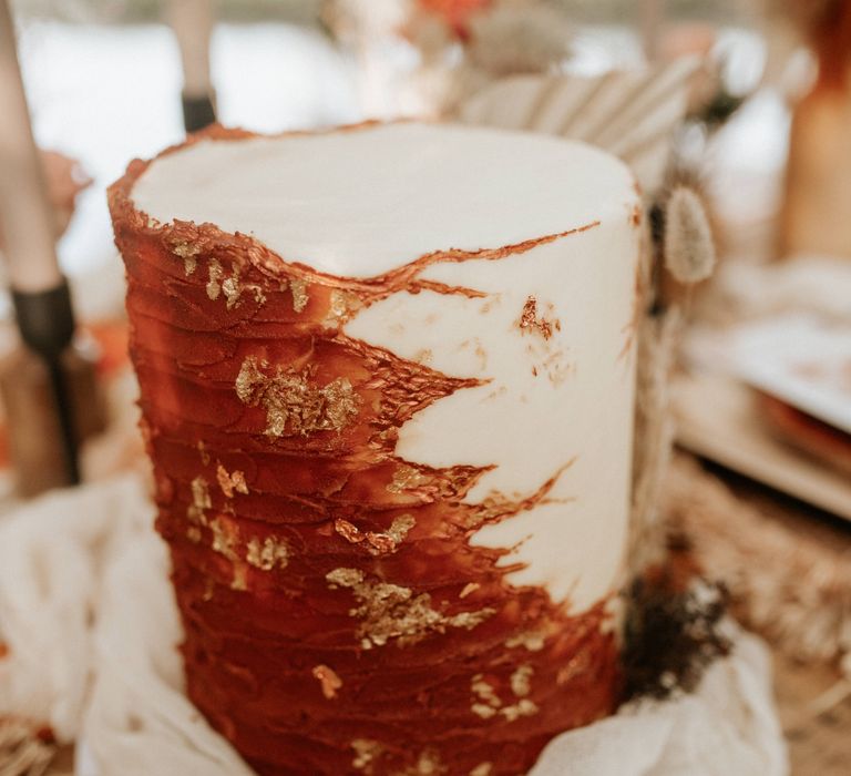 White and burnt orange wedding cake with gold leaf decoration 